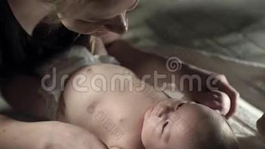 一个迷人的婴儿躺在床上，一位<strong>年轻</strong>的<strong>母亲牵</strong>着他的手